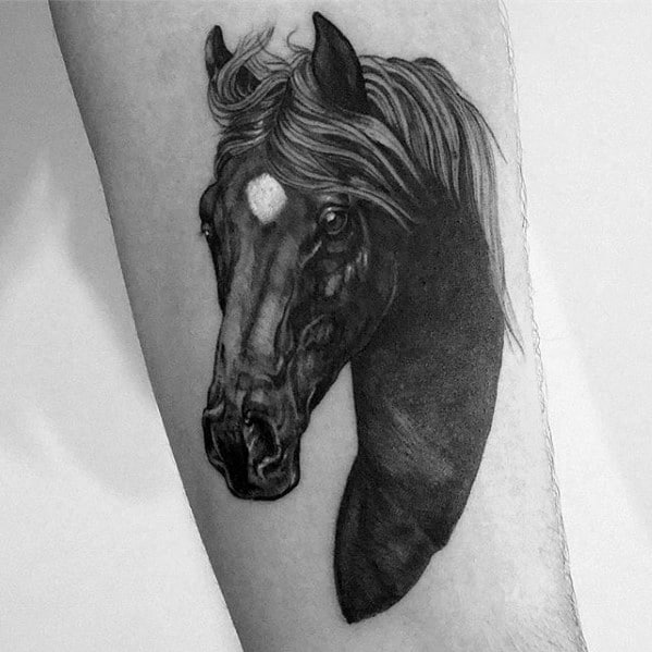 Realistic black and grey tattoo of a horse head with flowing mane and white forehead mark, placed on the forearm