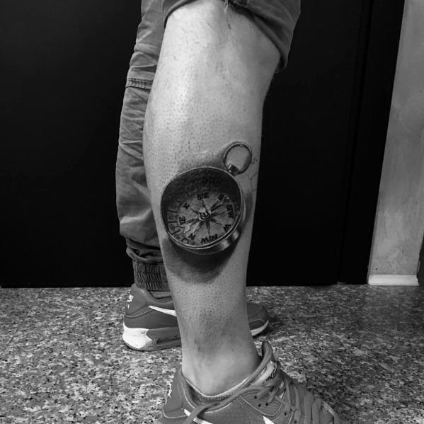 Hyper-realistic 3D compass tattoo on the leg, featuring intricate shading and depth, creating a striking illusion of a real object.