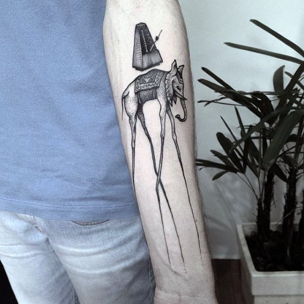 Black and grey Salvador Dali-style tattoo of a surreal elephant with spindly legs and a floating obelisk above, inked on the forearm.