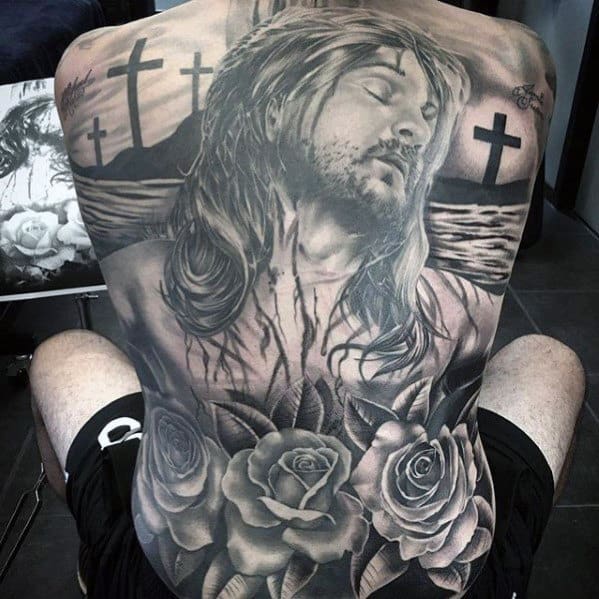 Man with a large back tattoo depicting Jesus, crosses, and roses