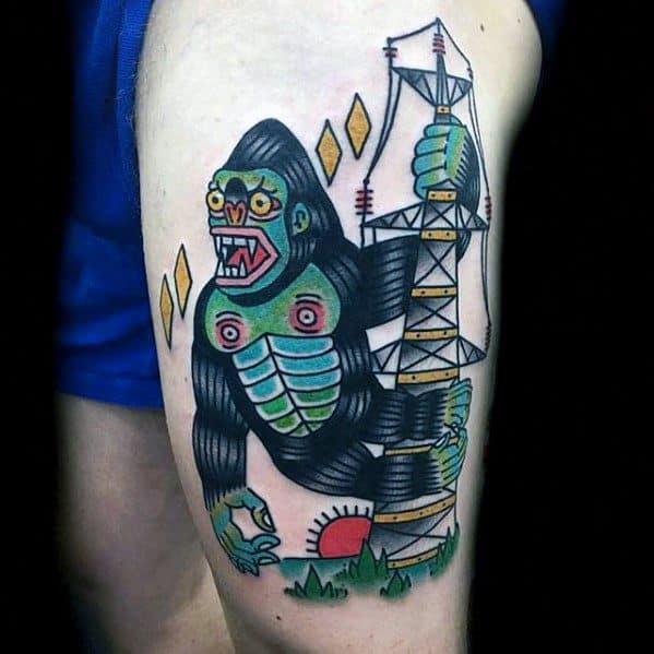 Neo-traditional King Kong tattoo with bold lines and bright colors, featuring Kong climbing a tower with sunset and diamond shapes.
