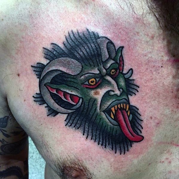 Classic Krampus tattoo on chest featuring a green-faced demon with curled horns, sharp teeth, fiery eyes, and a long red tongue.
