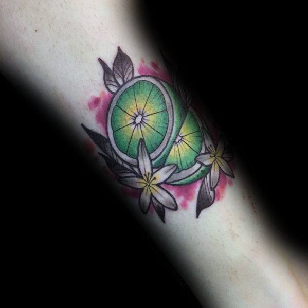Elegant lime slice tattoo with vibrant green shading, surrounded by delicate flowers and leaves, creating a fresh and tropical-inspired design.