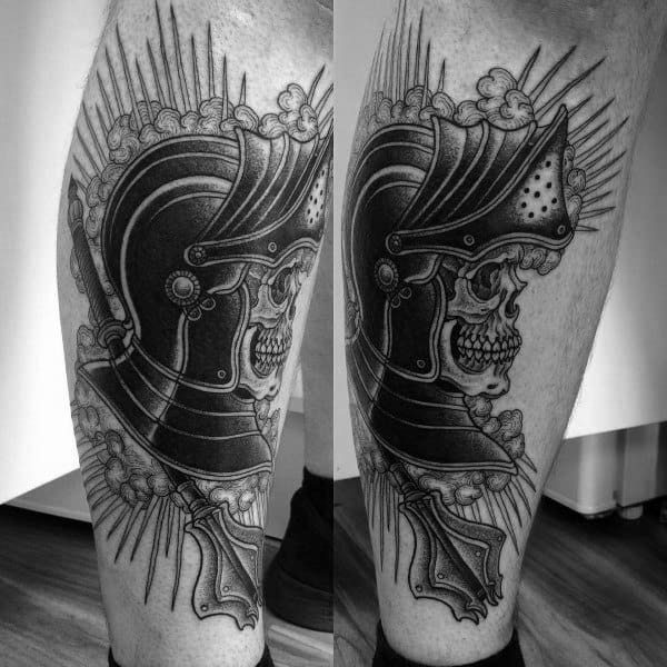 Detailed black and gray tattoo of a skull wearing a medieval knight’s helmet, with intricate shading and bold lines, symbolizing strength and valor.