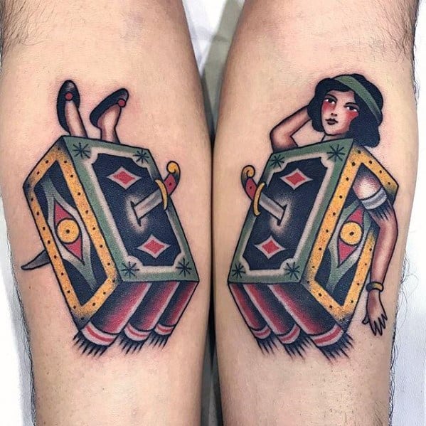 Matching tattoos of a woman performing a sword-through-box magic trick on forearms