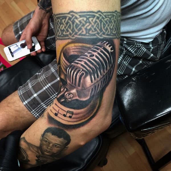 Guy With Microphone And Swirly Musical Notes Tattoo On Arms