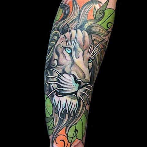 Neo-traditional lion tattoo on forearm with piercing blue eyes, flowing mane, and vibrant orange and green leaf background.
