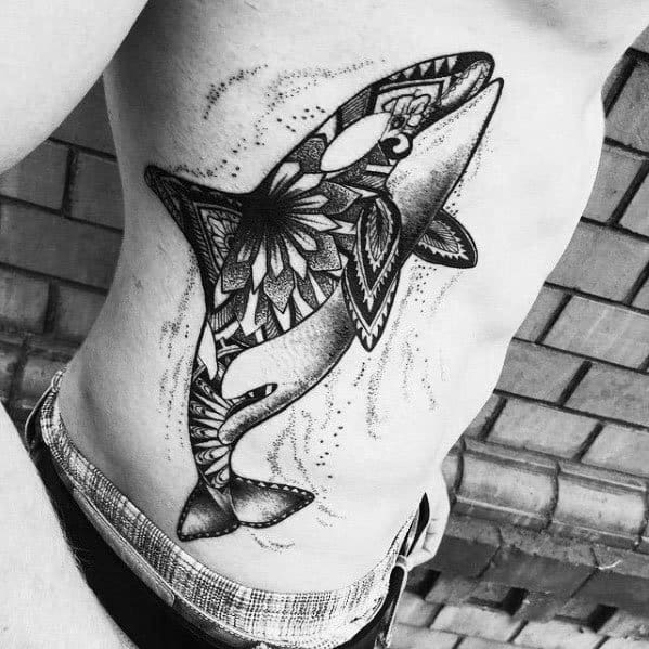 Black and gray orca tattoo on the side, featuring intricate mandala patterns within the whale's body, creating a striking and detailed design.