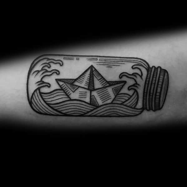 Paper boat tattoo inside a bottle with waves, symbolizing adventure, confinement, and the longing for freedom.