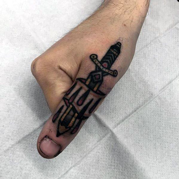 Tattoo of a dagger on a hand, with the blade running down the thumb like a sharp pencil sketch against a white surface