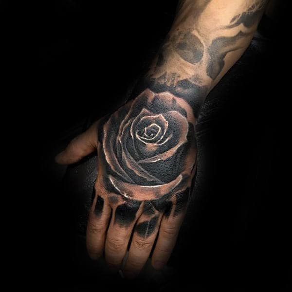 Hand with a realistic black rose tattoo