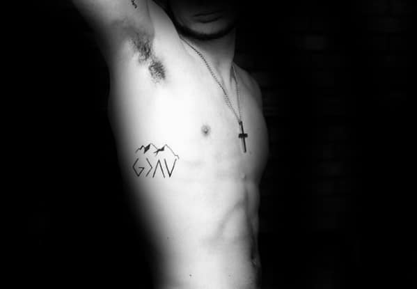 Side tattoo featuring "God is greater than the highs and lows" symbol with mountain outlines and minimalist design