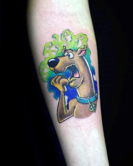Tattoo of a scared Scooby-Doo biting his paw, with a green and blue spooky mist swirling behind him.