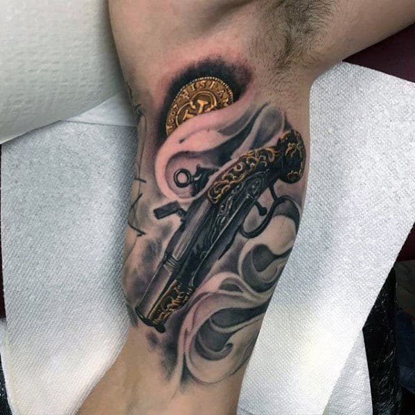 Realistic flintlock shotgun tattoo with intricate gold detailing and smoky effects, creating a bold and dramatic antique firearm design.