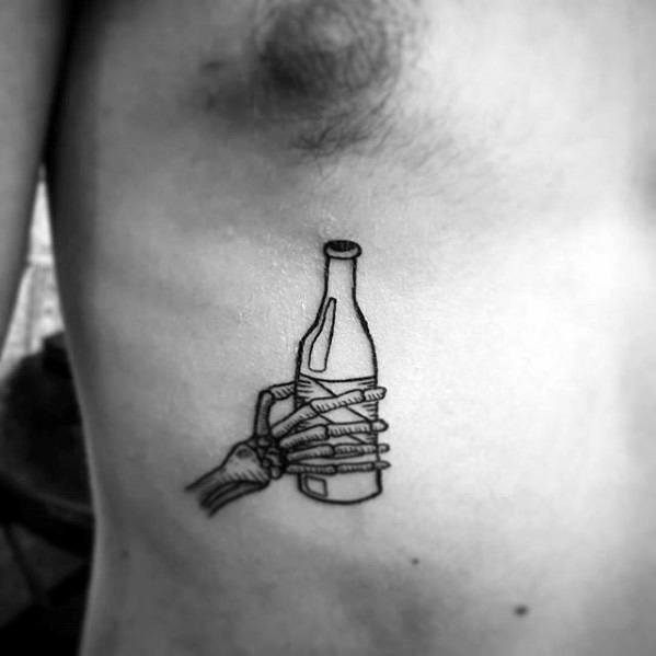 Minimalist linework tattoo of a skeletal hand gripping a bottle wrapped in a paper bag, placed on the ribcage for a bold and edgy look.
