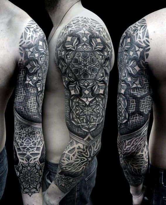 A black and grey full sleeve tattoo featuring intricate mandala patterns, geometric designs, and maze-like motifs, covering the shoulder down to the wrist with bold, symmetrical detailing
