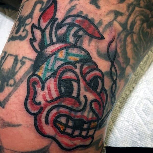 Blast over tribal tattoo featuring a colorful face with geometric patterns and feathers