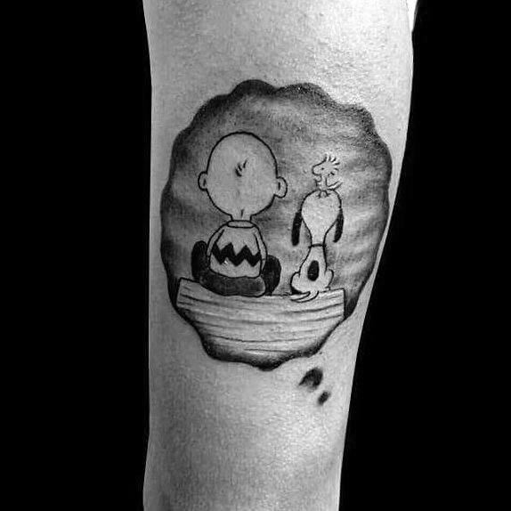 Black and white tattoo of Charlie Brown and Snoopy sitting on a dock, gazing into the distance, with a shaded circular background.