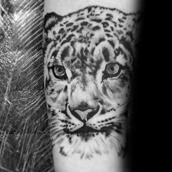 Black and gray snow leopard tattoo focusing on the face, with realistic shading and expressive eyes that convey calm strength.