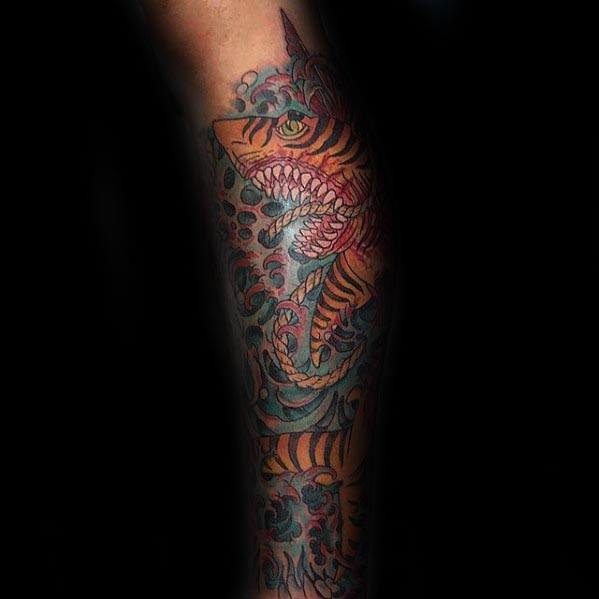 Colorful full-sleeve tiger shark tattoo with fierce details, swirling water patterns, and bold orange and teal tones for dramatic impact.