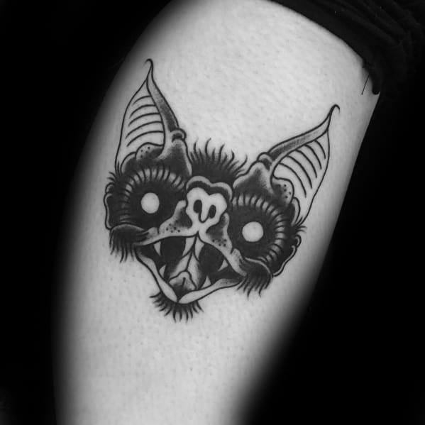 Blackwork bat head tattoo with glowing eyes, sharp fangs, and bold shading, creating a striking and eerie expression.
