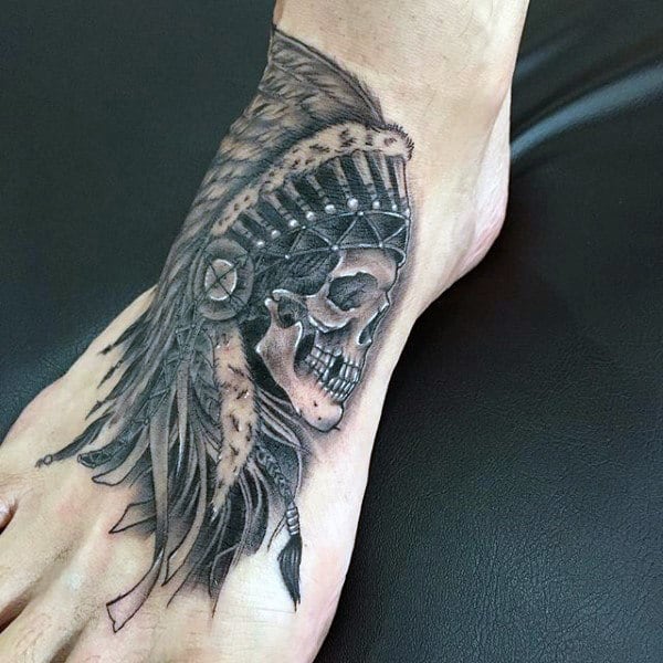 Foot tattoo showcasing a skull adorned with a detailed feathered headdress