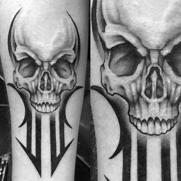 Skull tattoo with tribal elements on forearm, featuring sharp black arrows and curved lines extending from a detailed skull.