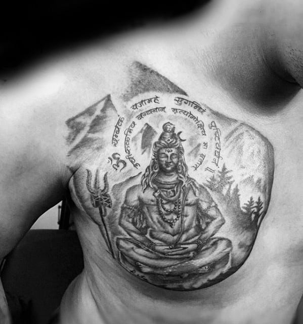 Chest tattoo of Lord Shiva in a meditative pose, with Sanskrit script and mountains in the background, featuring a trident on the side.