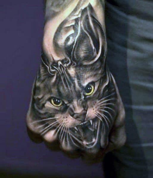 Hyper-realistic angry cat tattoo on the hand, featuring piercing green eyes and detailed fur for a bold and intense design.