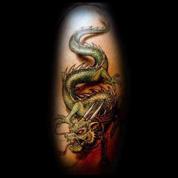 Tattoo of a green dragon with scales and fierce claws on a person's skin, set against a dark background
