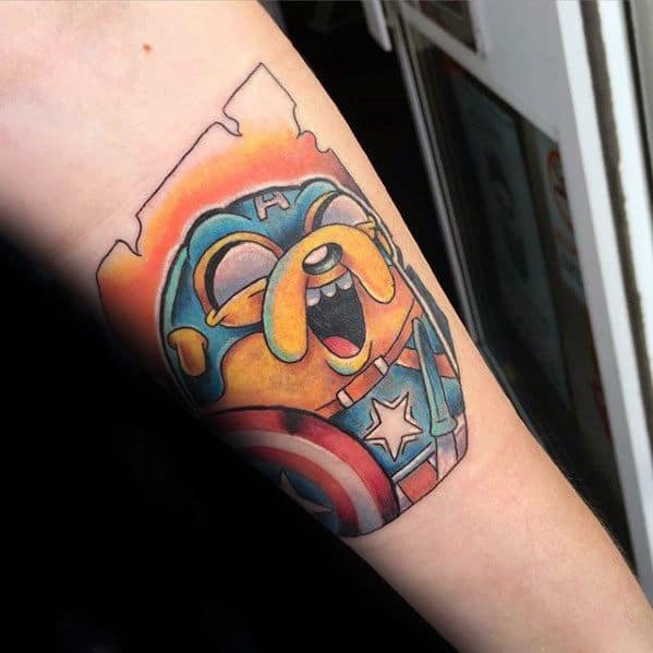 Adventure Time tattoo of Jake the Dog dressed as Captain America, complete with shield and helmet, inked on the inner forearm.