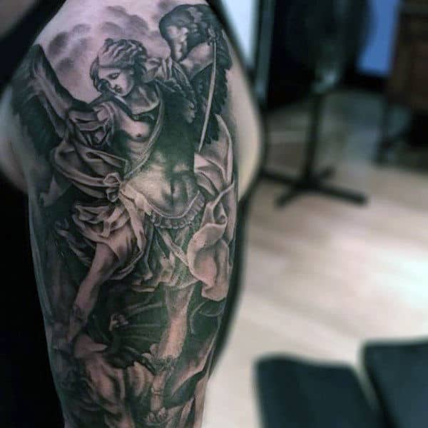 Detailed black and gray tattoo of an angel in battle on a person's upper arm