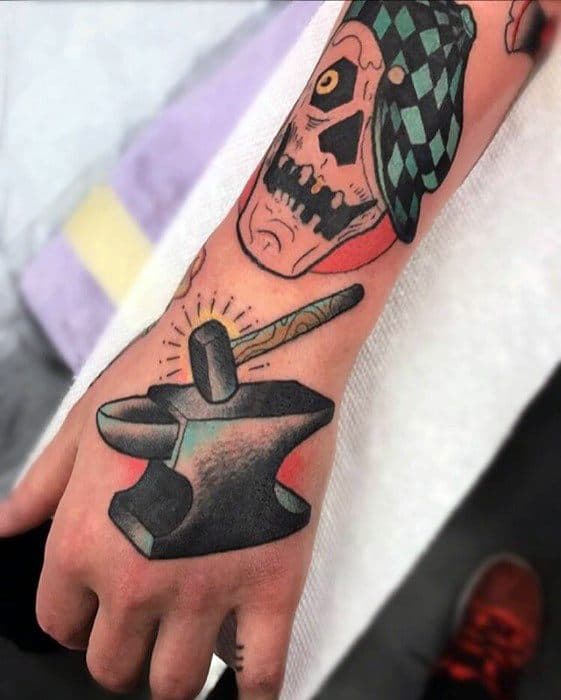 Colorful anvil tattoo on the hand with a hammer striking it, radiating yellow sparks, and bold shading for a dynamic, eye-catching design.
