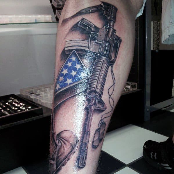 Realistic AR-15 tattoo on the leg, featuring an American flag, dog tags, and detailed shading, symbolizing patriotism, service, and strength.