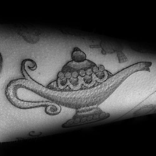 Genie lamp tattoo with ornate details graces an arm