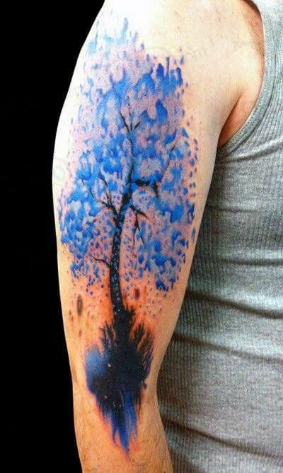Arm tattoo of a blue watercolor tree on the upper arm