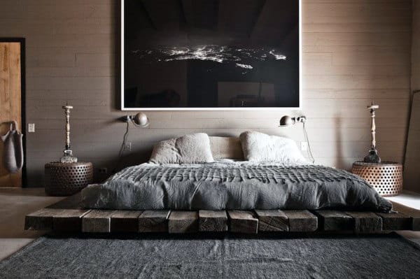 Modern bedroom with a low wooden platform bed, dark walls, and a large wall art piece.