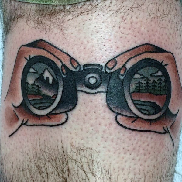 Traditional-style tattoo of hands holding binoculars, reflecting a scenic mountain and forest view, symbolizing exploration and adventure.