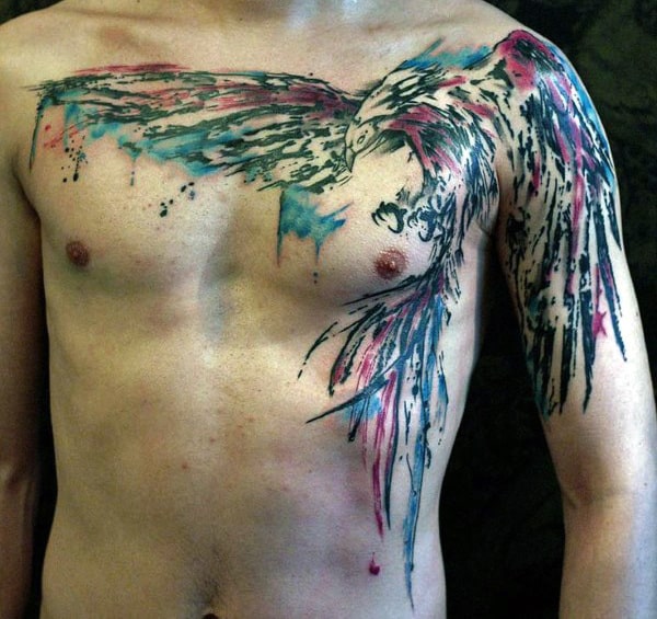 Abstract bird tattoo in colorful watercolor style on a shirtless man's chest and shoulder
