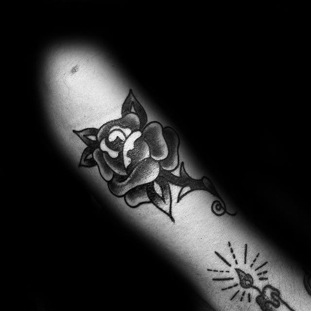 Black rose tattoo on an arm