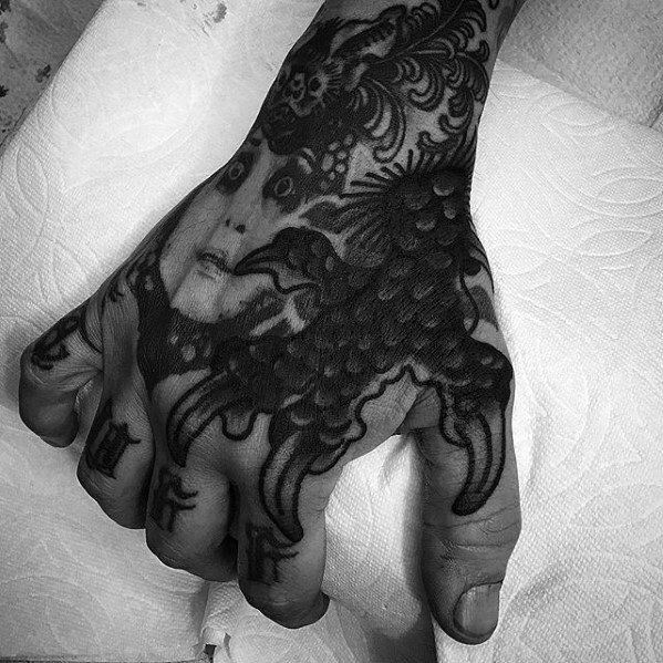 Hand with intricate blast over tattoo of a face and animal design