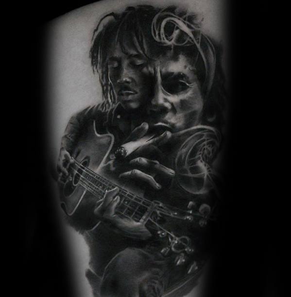 Black and gray tattoo of Bob Marley playing guitar and smoking, with layered imagery and soft shading creating a dreamlike, double exposure effect.