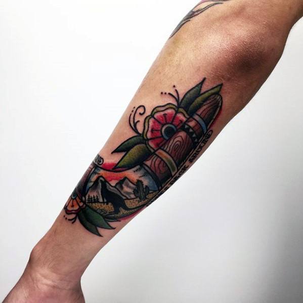 Boomerang tattoo featuring a mountain landscape, floral accents, and a sunset sky, wrapped around the inner forearm.