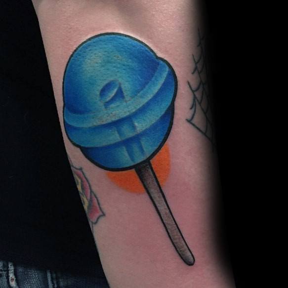 Bold blue lollipop tattoo with smooth shading and a subtle 3D effect, creating a vibrant and playful candy-inspired design on the arm.