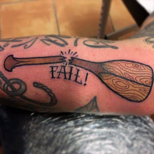 Alt text: Tattoo of a canoe paddle with the word "FAIL!" in bold letters, emphasizing a playful and humorous design.