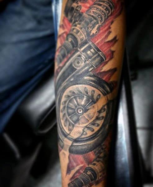Tattoo on an arm featuring a detailed mechanical design with gears and pistons against a fiery background