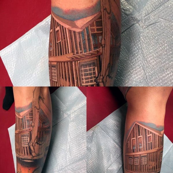Detailed tattoo of a wooden house under construction, featuring beams and scaffolding, symbolizing craftsmanship, dedication, and the art of building.