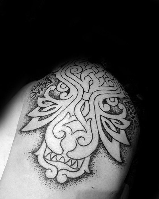 Celtic wolf tattoo on upper arm with thick black outlines, knotwork details, and dot-shading creating a bold, stylized wolf face.