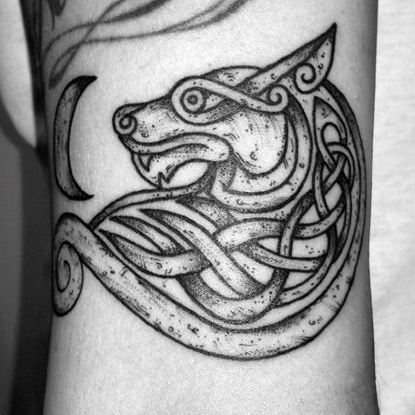 Dotwork Celtic wolf tattoo with a snarling wolf head, crescent moon, and intertwining knot patterns forming a circular design.