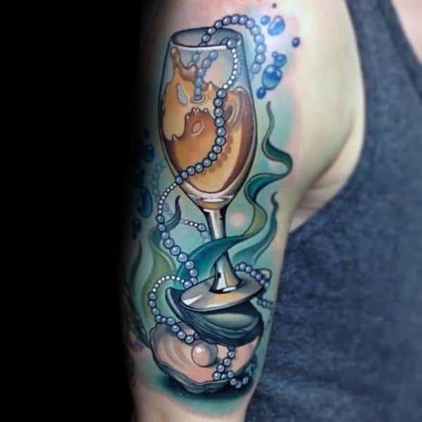 Tattoo of a pearl-filled goblet inside an oyster shell with pearls and bubbles on a man's upper arm.